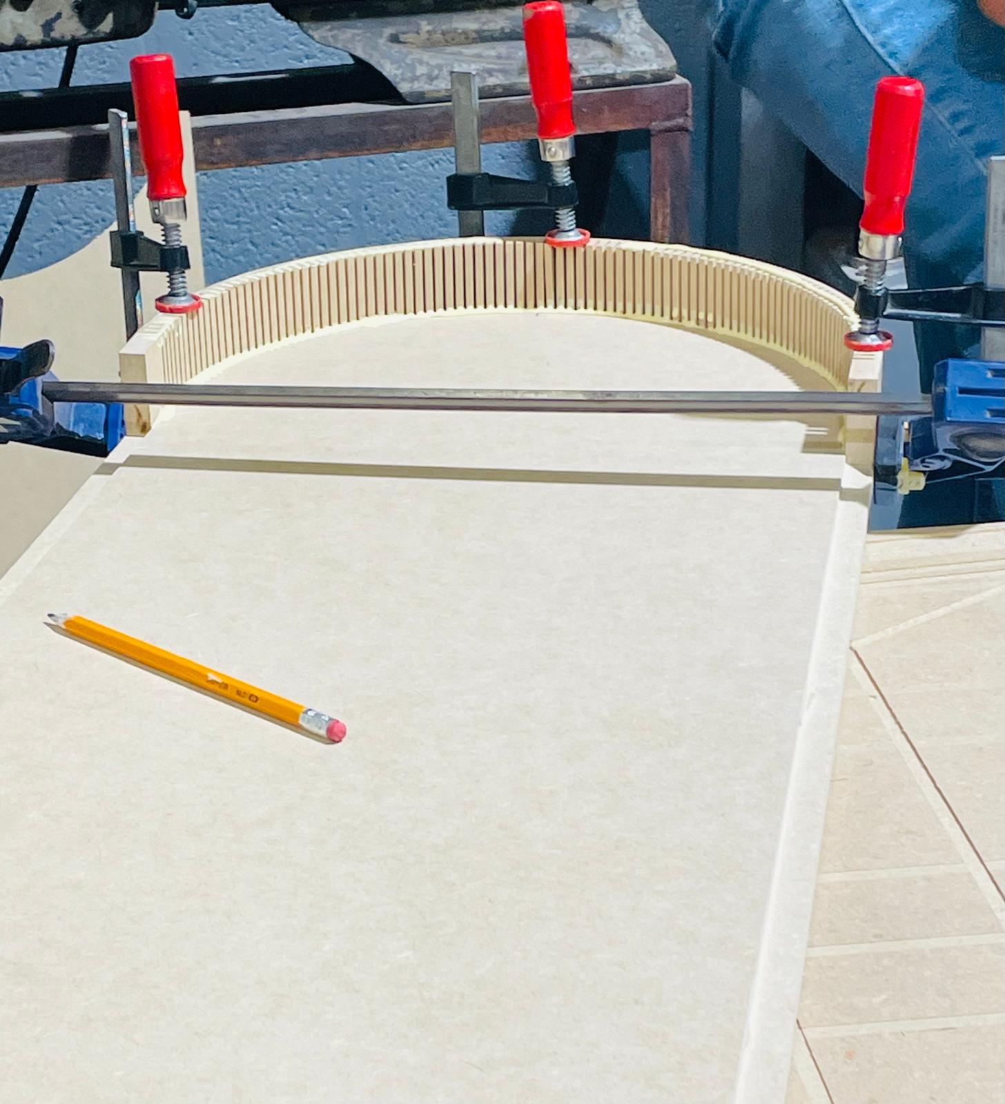 Panel de MDF curvado con cortes de kerf sujeto con prensas